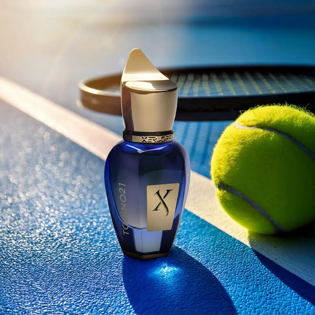 Blue and gold Xerjoff fragrance bottle beside a tennis ball